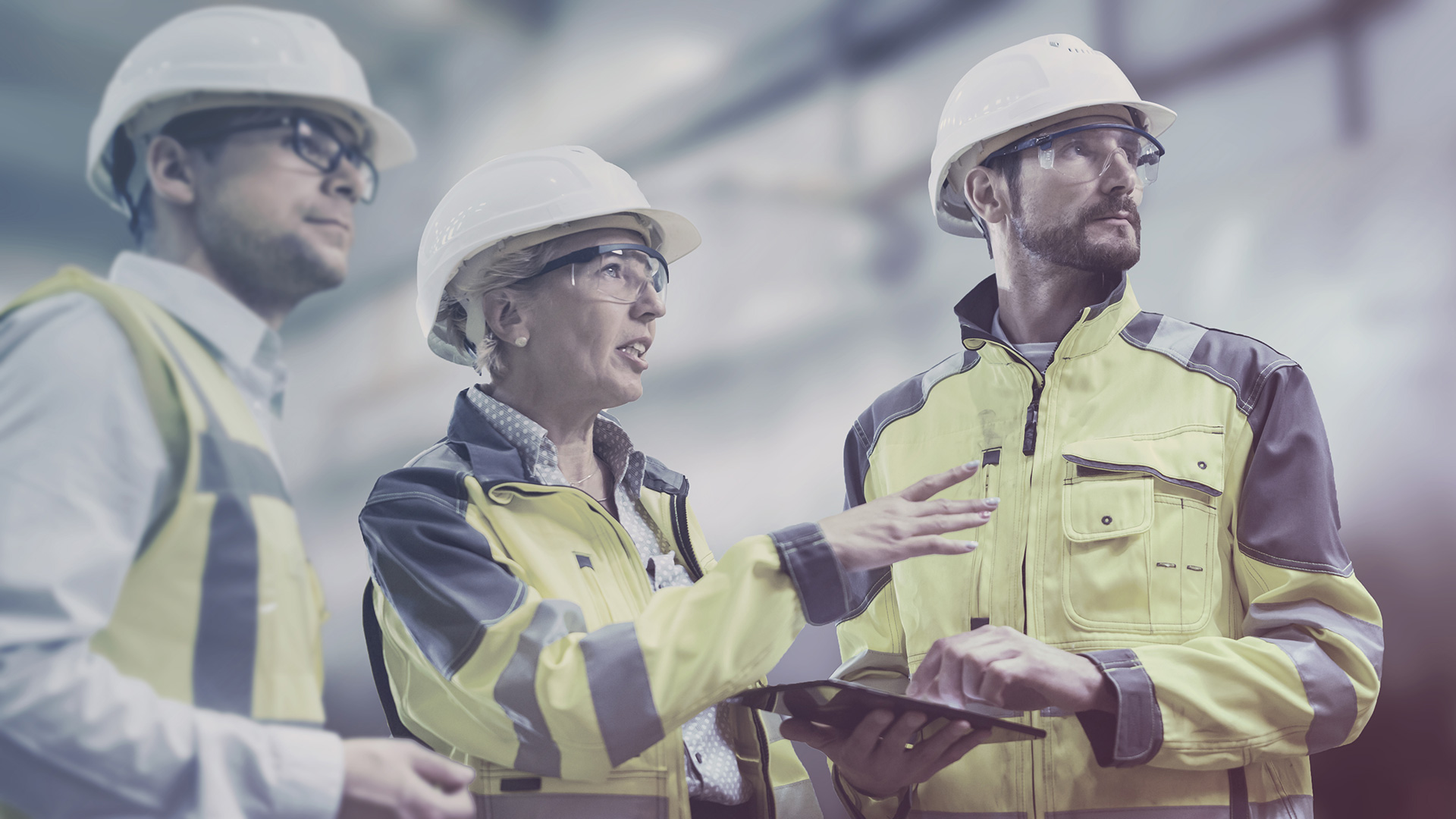 Three workers in hard hats looking in the same direction